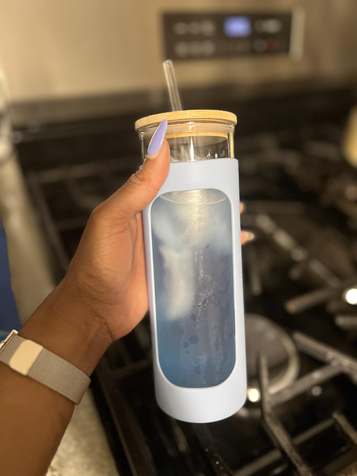 Hand holding a slim bottle with icy blue Tavo LiquidHydrate liquid hydrate electrolyte drink in the kitchen.